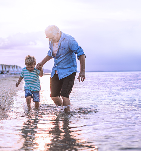 Un homme âgé tenant un enfant par la main sur une plage