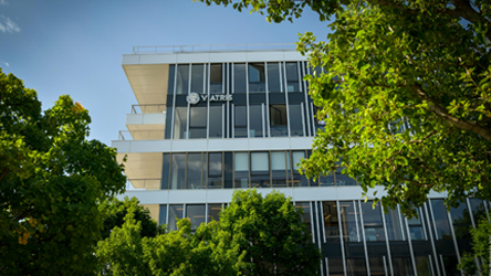 Façade du siège de Viatris à Lyon, avec le logo Viatris visible et des arbres en premier plan